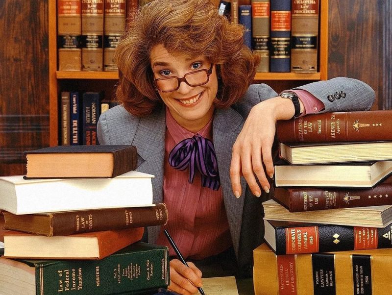Женщина в библиотеке со стопкой книг