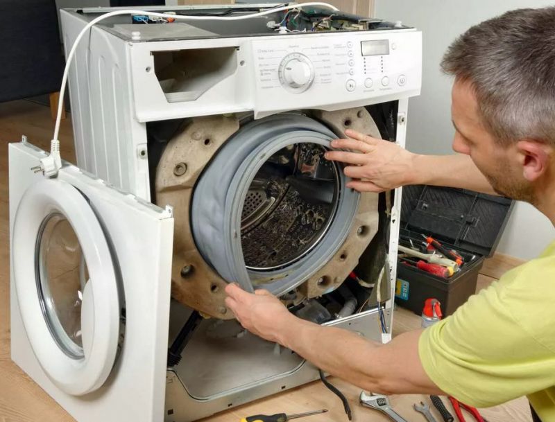Мастер демонтирует стиральную машину